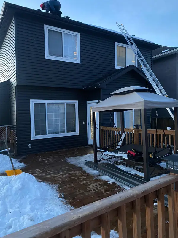 Back of a home re-sided in charcoal with white window trim