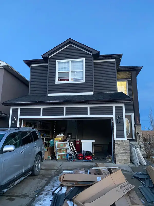Dark siding installation in progress on a two-storey home