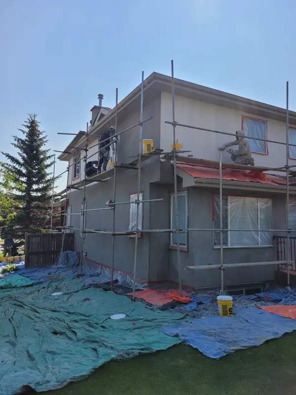 Stucco repair in progress with scaffolding on a Calgary home